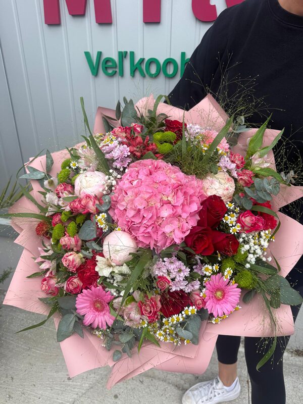 Veľká luxusná kytica s ružovou hortenziou, červenými ružami, pivonkami, gerberami a eukalyptom pred prevádzkou M Flower